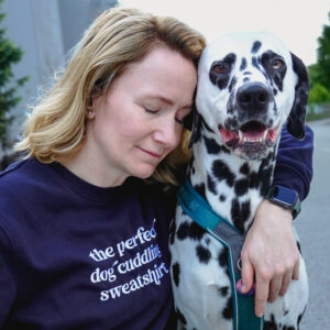 Žena grli psa i nosi majicu "The perfect dog cuddling sweatshirt"